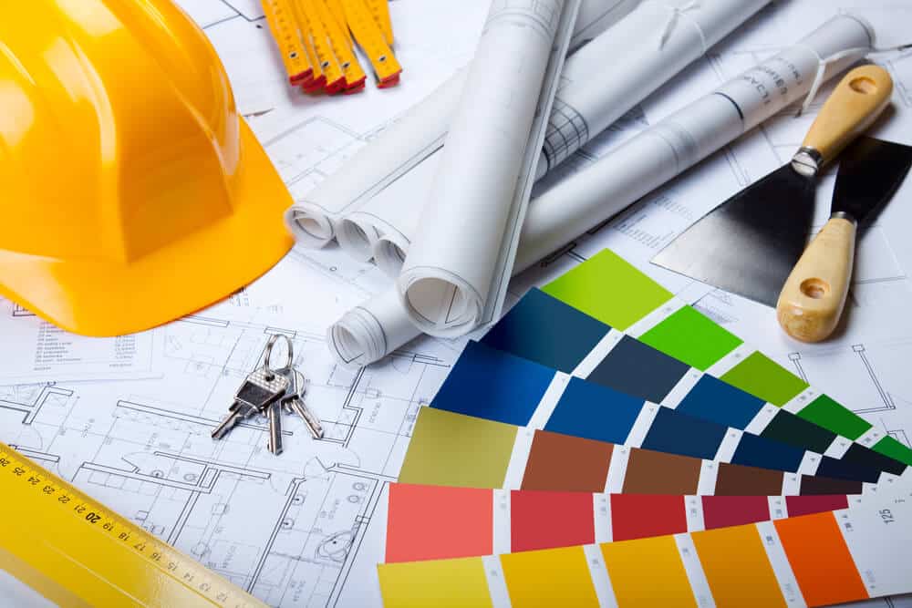 Architectural plans, colour swatches, keys, and construction tools on a table, illustrating Smartway Builders' meticulous planning process.